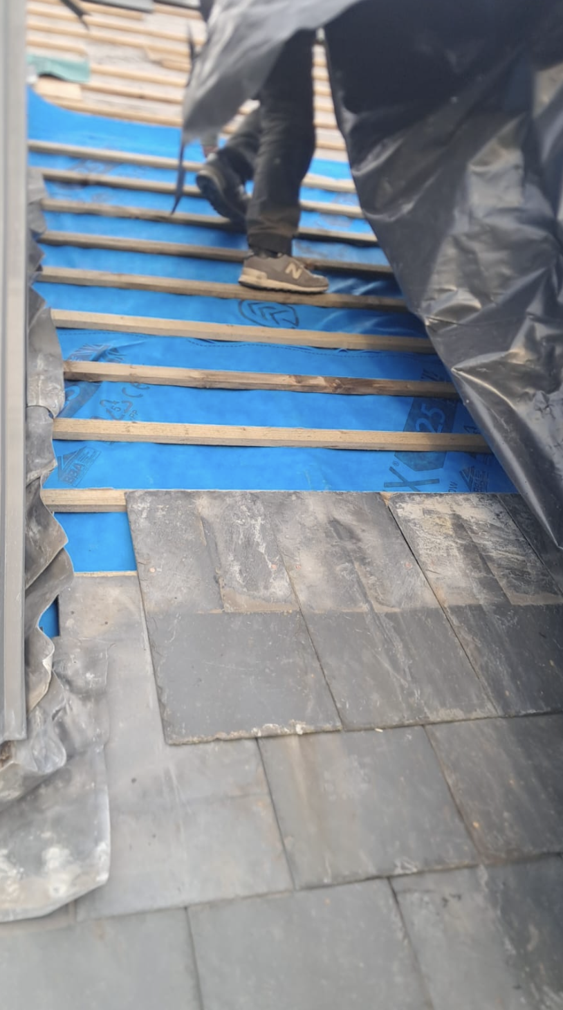 Slates being re-laid over blue breather membrane and battens