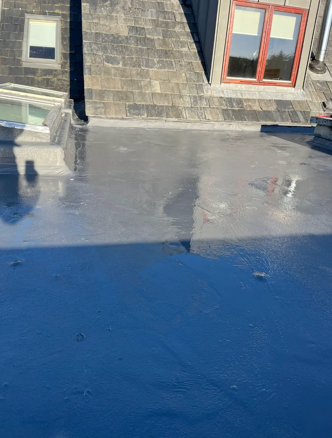 Freshly coated flat roof terrace beside slate pitched roof